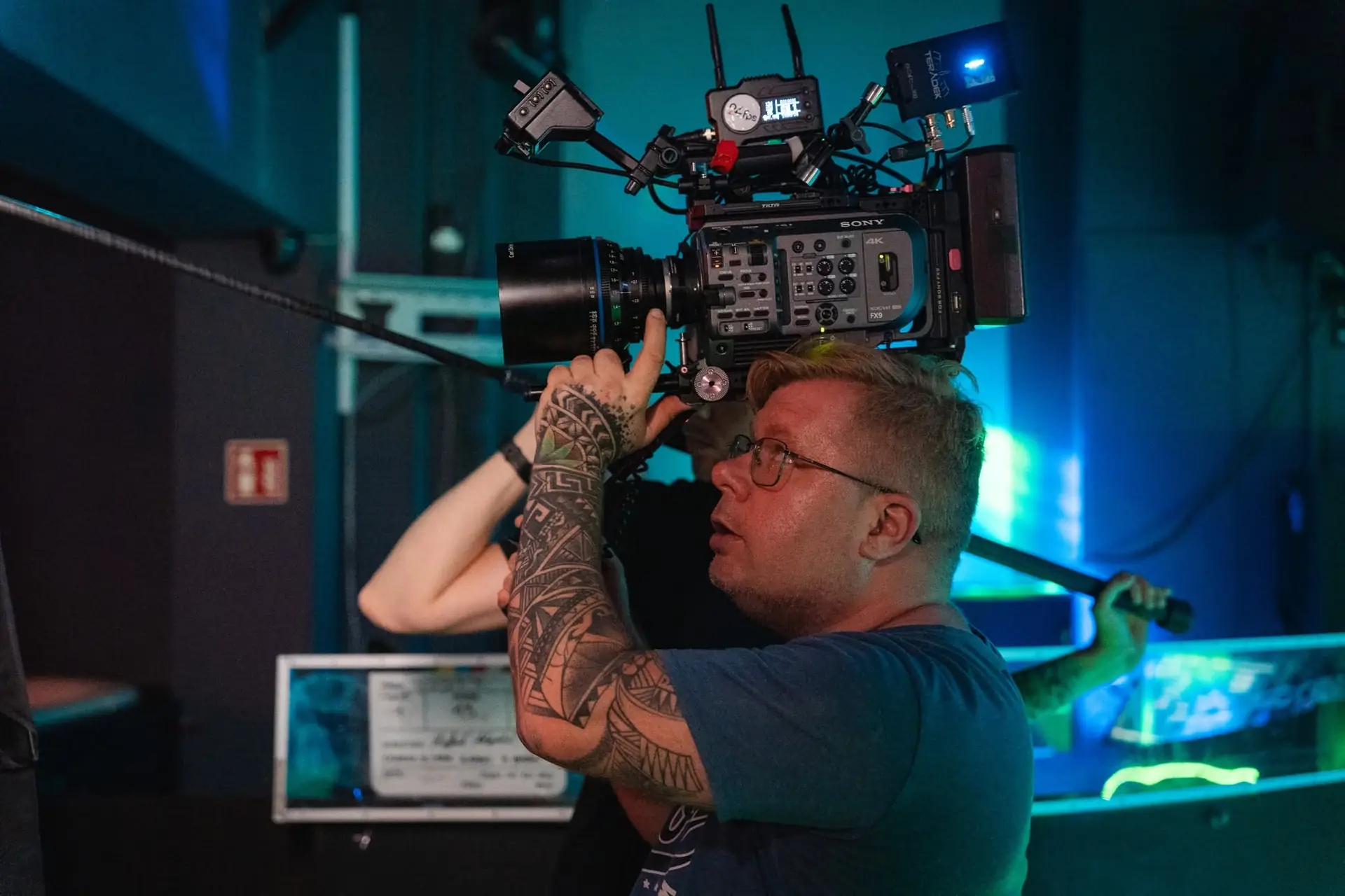 Łukasz Nyks z kamerą filmową na ramieniu